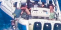 A video still of boaters dumping trash off a boat into the ocean