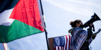 A demonstrator with a U.S. flag and Palestinian flag.