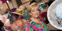 Carol Hampton stands among racks of Derby hats inside her store.