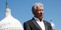  Mario Andretti listens during a news conference with the Capitol seen in the background