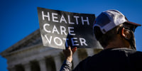 A supporter of ACA stands in front of the Supreme Court with a sign that reads 'HEALTHCARE VOTER.'