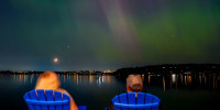 People view the northern lights, or aurora borealis over a lake in Washington