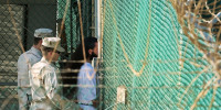 Guards walk behind a detainee 