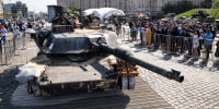 People look at a damaged U.S.-made M1 Abrams tank