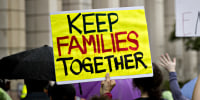 A demonstrator holds a sign that reads "Keep Families Together."