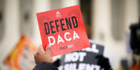 Immigration rights activists with a sign that reads 'DEFEND DACA.'