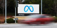 A red car drives by the Meta sign at the company's headquarters in Menlo Park