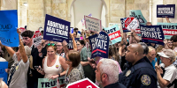 People holding signs for and against abortion inside of a court chamber