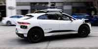 A white Waymo robotaxi vehicle driving on the street