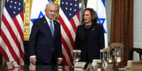 Benjamin Netanyahu and Kamala Harris stand next to each other in a conference room, their reflections are seen on the table in front of them