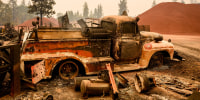 An old fire truck smolders after getting burned during the Park fire in the Paynes Creek area of unincorporated Tehama County, California, on Saturday.