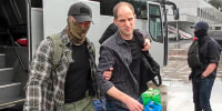 Wall Street Journal reporter Evan Gershkovich is escorted by a Russian Federal Security Service agent as they arrive at an airport outside Moscow on Aug. 1, 2024. 