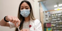 A pharmacist prepares a Moderna Spikevax COVID-19 vaccine.