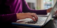 A woman sits at a laptop.