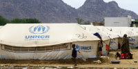 Sudanese already displaced by conflict, walk near tents at a makeshift campsite they were evacuated to following deadly floods Kassala on August 12, 2024.