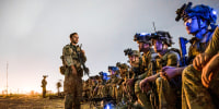 Soldiers sit and stand outside