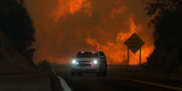 The Line Fire jumps highway 330 as an emergency vehicle is driven past Saturday, Sept. 7, 2024, near Running Springs, Calif.