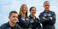 The four crew members smiling as they pose for a photo