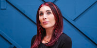 Laura Loomer sits on a blue couch against a blue wall