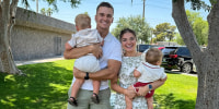 Matt and Abby Howard pose for a portrait outside on a lawn with their two children.