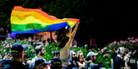 A participant holds a rainbow flag next to police officers