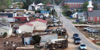 An aerial view of vehicles passing flood damage