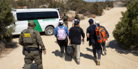 Asylum seekers walk towards a Border Patrol van