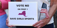 A woman holds a sign to vote no for proposition 1 