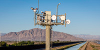 Cameras on a surveillance tower monitor, mountain landscape in the distance