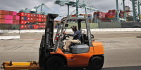 A worker drives a forklift near shipping containers at the Port of Los Angeles on Sept. 20, 2024.