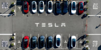 Tesla vehicles line a parking lot 