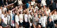 Female lawmakers dressed in white pose for a photo