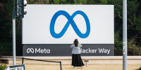 A visitor takes photographs of Meta Platforms signage outside the company's headquarters in Menlo Park