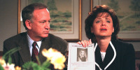 John Ramsey looks on as his wife Patricia holds up a flyer promising a 100,000 USD reward for information leading to the arrest and conviction of the murderer of their daughter.