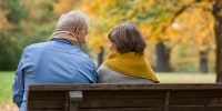 Rear view on Senior couple sitting on park bench in autumn