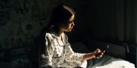 Teen girl on phone in bedroom stock photo. 