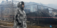 A woman stands by a house destroyed by a drone strike in Kharkiv