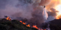 Water is dropped by helicopter on the advancing Palisades Fire