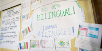 A sign says "We are bilingual! Somos bilingues!" on a classroom board