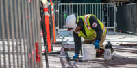 A construction worker repairs a brick sidewalk