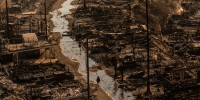 A person walks amid the destruction left behind by the Palisades Fire