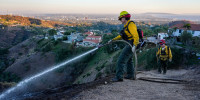 A Firefighter sprays water over a hillside