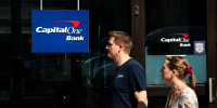 People walk past a Capital One bank