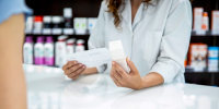 pharmacist handing a box of medicine to a customer in a pharmacy