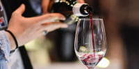 An exhibitor pours a glass of red wine