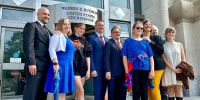 A group of people stand for a photo outside of a courthouse