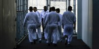 Detainees walk toward a fenced recreation area