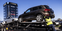 A worker loads vehicles onto a transporter at a Carvana vending machine location