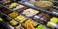 A bakery display case with various colored cookies.