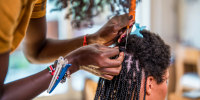 A person gets her hair braided.